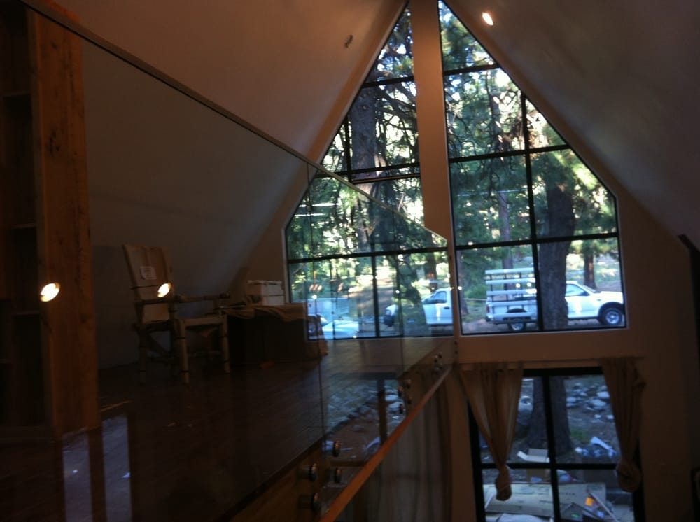 A-frame gable window wall with a frameless glass loft railing in the foreground