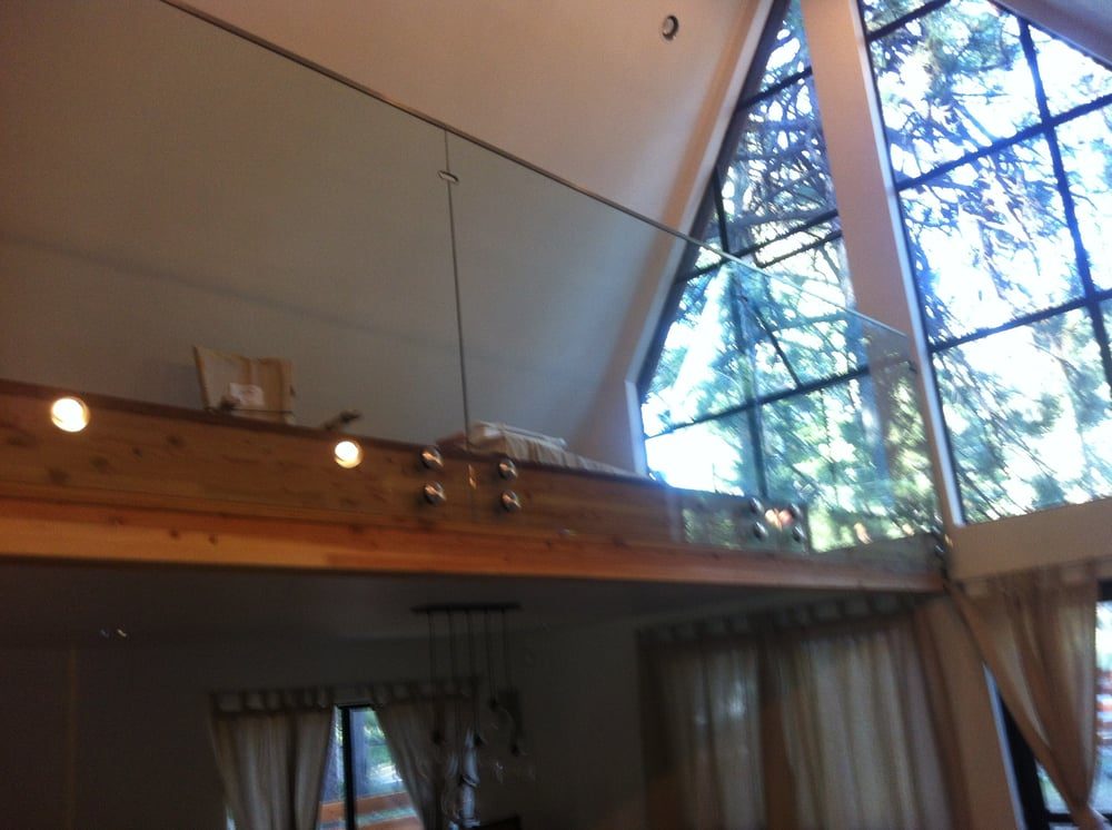 Frameless glass loft railing on standoffs beneath an A-frame gable window