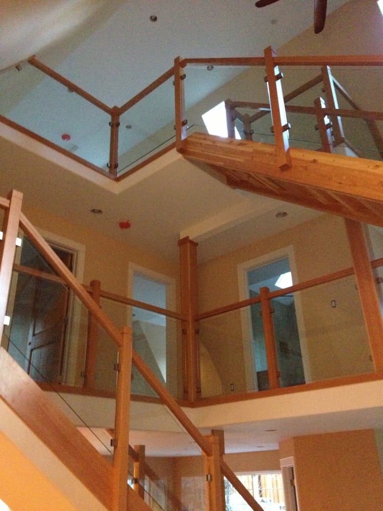 Two-story timber staircase with glass railing panels between wood posts